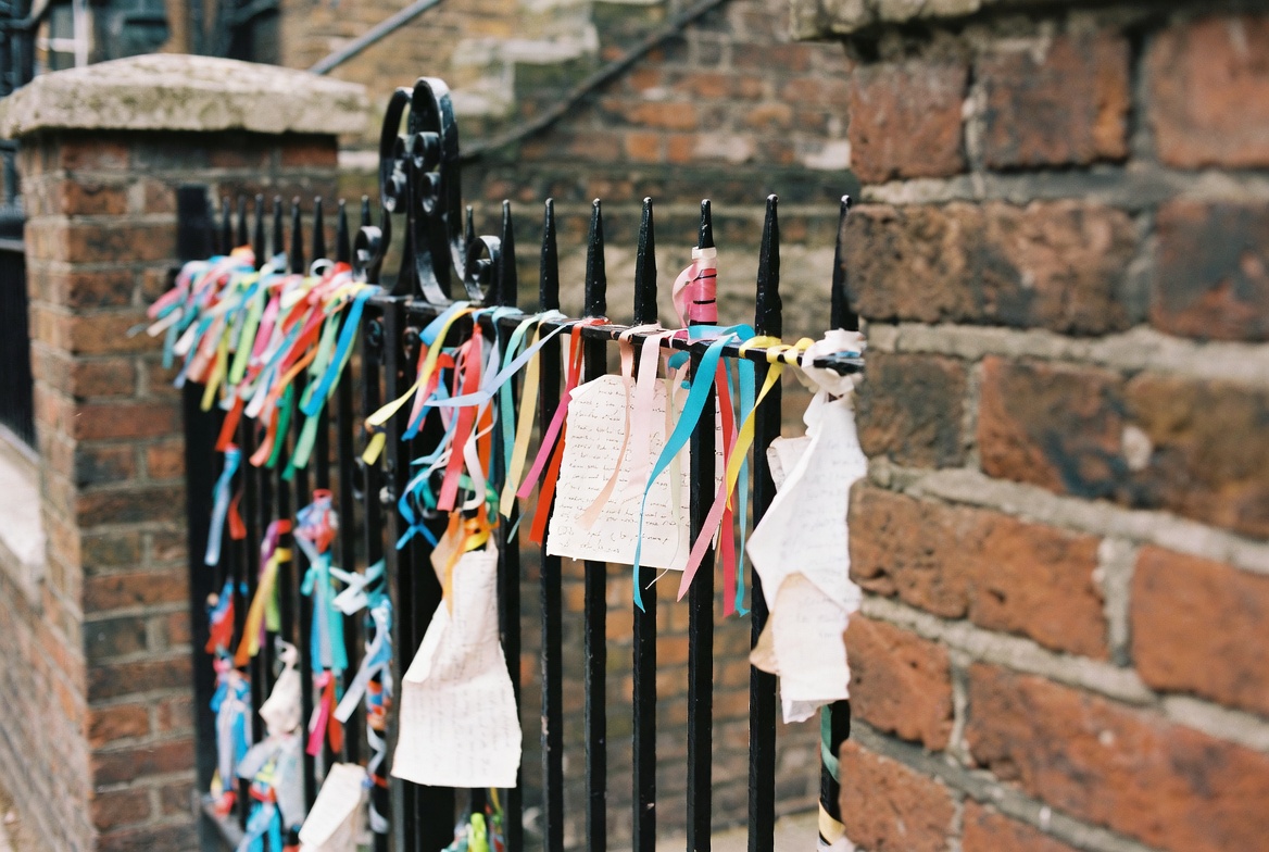 The iron gate of Crossbones Garden hung with memorial ribbons.